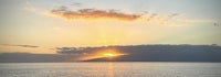 the sun is setting over a body of water with mountains in the background